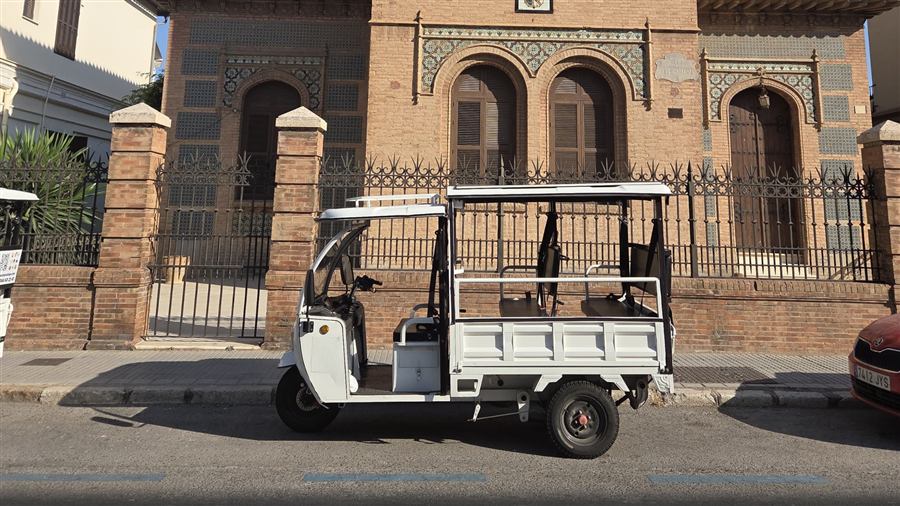 Tuk tuk in front of a traditional tiled façade in Málaga
